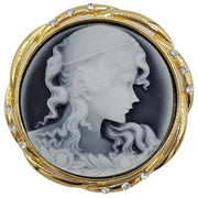 Broche colgante camafeo redondo en metal dorado. Figura mujer color crema con fondo gris. Rodeado de brillantes de strass. Diámetro de 4,5 cm. Se puede usar como colgante.