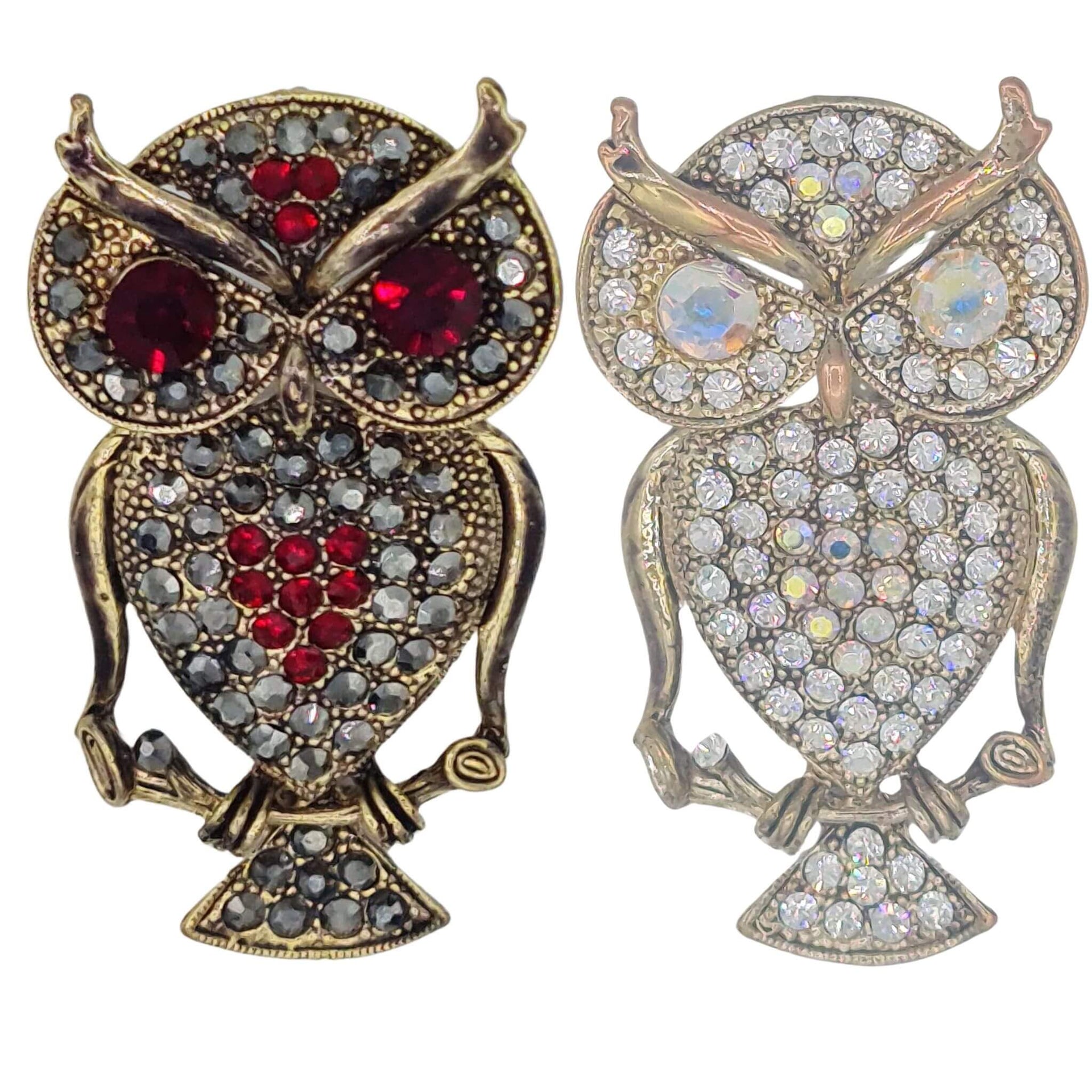 Broche buho colgante de metal dorado y brillantes de strass en color blanco. Trasera en color oro viejo con alfiler y seguro. Puede usarse también como colgante con una cadena ya que lleva una argolla en la parte superior. Mide 6 cm de largo x 3 cm de ancho.