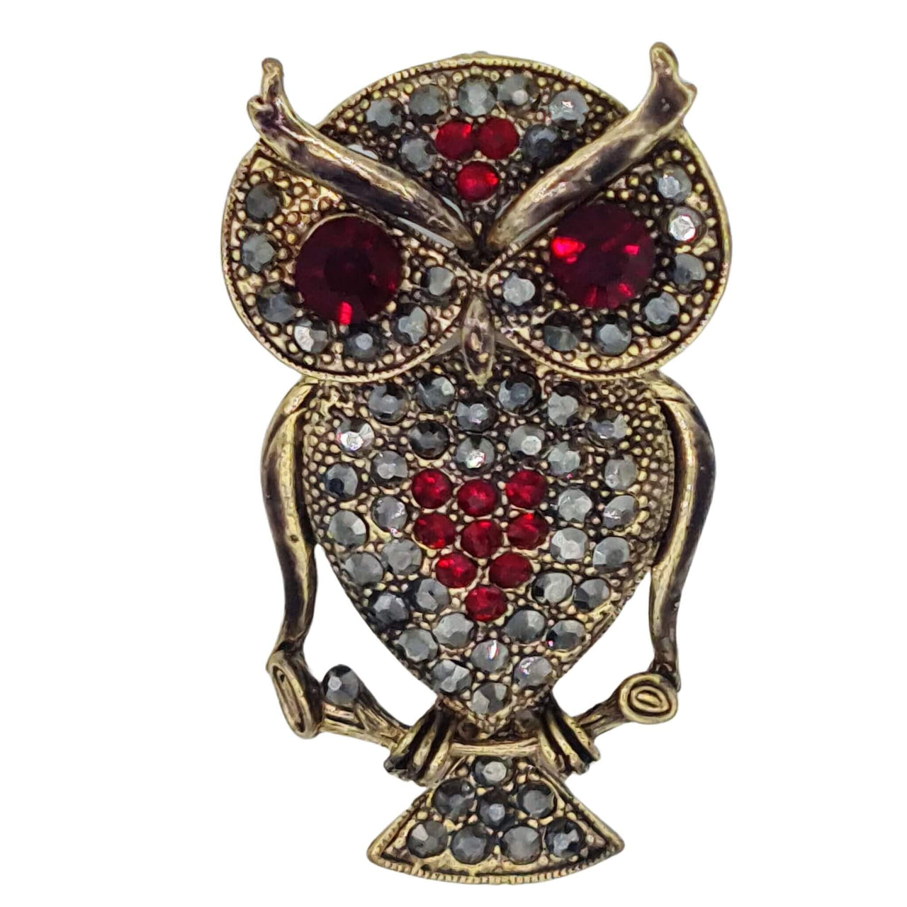Broche colgante  buho de metal dorado y brillantes de strass en color rojo. Trasera en color oro viejo con alfiler y seguro. Además del alfiler habitual, lleva una pieza que permite usarlo como colgante. Mide 6 cm de largo x 3 cm de ancho.