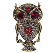 Broche colgante  buho de metal dorado y brillantes de strass en color rojo. Trasera en color oro viejo con alfiler y seguro. Además del alfiler habitual, lleva una pieza que permite usarlo como colgante. Mide 6 cm de largo x 3 cm de ancho.