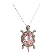 Broche colgante tortuga con brillantes rosas de strass y metal plateado en la parte trasera. Puede usarse también con una cadena como colgante ya que lleva una argolla en la parte superior. Mide 8 cm de largo x 5 cm de ancho.